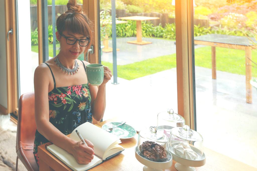 Woman writing in a gratitude journal at a table.