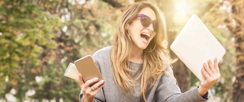 Woman stressed holding a laptop and two phones